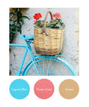 Blue bicycle with a wicker basket full of flowers against a textured wall.