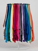 A display of many draped fabric or scarf-like pieces in different colors hanging from a circular stand on a white floor against a light gray wall. The visible colors include brown, white, blue, teal, green, red, pink, purple, gray, black, and orange.