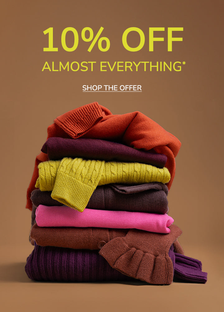 A promotional sale graphic with the text '30% OFF TUESDAY - SUNDAY' and 'SHOP THE OFFER' above a stacked pile of folded knit sweaters in orange, burgundy, yellow, dark plum, brown, and pink on a warm tan background.