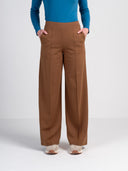 Person wearing brown wide-leg pants and a blue top on a white background